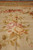 Detail of hand-woven pink and cream roses with olive leaves on the pileless tapestry surface