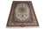 Signed Isfahan rug 5'2" x 7'3" photographed at an angle showing silky sheen across the ivory field