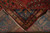 Back of the antique rug folded over to reveal hand-knotting, cotton foundation and ivory fringe