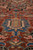 Low angle pile shot revealing blue pendant motif and dense hand-knotted wool texture