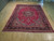 12' x 14'10" Persian Sarouk rug laid on light hardwood floor showing full red field