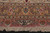 Woven cartouche signature sits above the ivory fringe at one end of the rug
