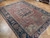 9x12 antique Heriz Serapi rug angled on parquet, showing low pile and salmon abrash