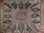 Close-up of ivory and camel stepped medallion with navy hooked palmettes at rug center
