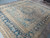 10x13 antique Persian Kermanshah rug angled on tile, showing sky blue field and indigo border