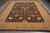 Hand-knotted Ziegler style wool rug photographed lengthwise on grey floor with ivory fringe visible