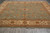 12' x 12' Oriental rug on grey tile floor showing green field and ivory border