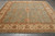 Angled view of square hand-knotted wool rug with all-over palmette design and wide border