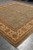 Corner perspective showing golden rust palmettes scrolling across the soft green field of this rug