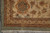 Corner of ivory border with rust rosette, olive edge and clean cotton fringe