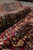 Rolled edge of the burgundy area rug showing thick wool pile depth and border layers