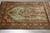 Overhead angled view of sea green Qum silk rug on grey tile, birds and blossoming branches