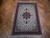 Ivory and burgundy 7x10 Tabriz rug displayed on herringbone parquet wood floor in daylight