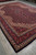 Corner perspective showing ivory fringe, navy selvedge and three layered borders on hand-knotted wool