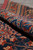 Rolled edge of the antique rug showing indigo pile depth, red selvedge and wool texture