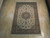 6'7" x 9'8" Tabriz rug displayed on light wood floor showing ivory field and green borders