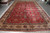 Deep red all over floral Tabriz rug photographed flat on warehouse floor showing full pattern