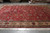 Red and ivory 11x18 hand-knotted Persian rug seen lengthwise with arabesque vine field