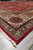 Low angle corner shot of red palace rug with cream border and green outer stripe