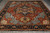 Full length view of the rust Serapi rug on grey flooring with ivory fringe ends