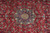 Close-up of the ivory and navy star medallion with salmon center on red wool