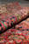 Rolled edge of the wool Persian rug showing plush pile depth and multicolored floral border