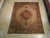 Beige and salmon Heriz rug photographed on light wood floor showing complete geometric layout