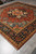 Corner perspective showing geometric medallion, light blue spandrels and dense wool pile on tile floor