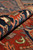 Rolled edge close-up showing navy border, rust field and the soft wool pile depth