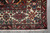 Corner detail showing ivory border diamonds, rust guard stripes and tight selvedge on grey floor