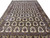 Angled floor shot showing repeating ivory panels, sage ground and camel gold border detail