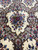 Macro of a single ivory cartouche holding a burgundy, blue and gold flower bouquet