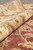 Rolled edge of the wool rug showing deep ivory border pile and soft rose field