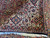 Folded corner revealing thick wool pile, navy outer border and ivory corner detail with cotton fringe