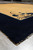 Corner perspective of navy border, curling lotus spray and gold field with hand-knotted wool pile