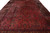 Close angled view of red field with navy vases, palmettes and camel gold border detail
