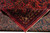 Folded corner reveals cotton foundation back and fine knotting beside the silky burgundy wool pile