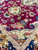 Corner detail of navy palmette border meeting magenta field scattered with blue and pink blossoms