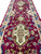Close perspective of ivory medallion with pink, green and gold floral sprays on maroon ground