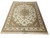 Angled floor view highlighting sage green corner spandrels, ivory floral field and camel outer border