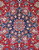 Close-up of navy blue stepped medallion with pink rosettes and olive leaves on red