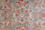 Macro weave shot showing pink, green and rust flowers knotted into soft blue wool pile