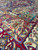 Angled close-up showing dense wool pile, teal panels and ivory floral cartouches in raking light