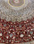 Close up of deep red silk field with curling vines, ivory blossoms and medallion edge