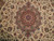 Detail of the rust and salmon star medallion surrounded by dense ivory floral scrollwork