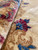 Close-up of dense wool pile folded back revealing crimson, blue and green floral detail