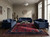 Burgundy Art Deco rug anchoring a living room with navy velvet sofas and bronze sculptures
