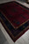 Angled full view of hand-knotted wool Art Deco rug with deep burgundy field and navy borders