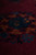 Low angle macro of the medallion showing orange, teal and indigo wool with glossy sheen