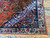Navy border with red palmette, ivory guard stripe and yellow fringe on this hand knotted wool rug